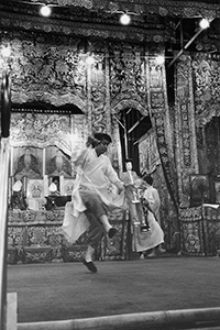 Ritual practitioner with bell and paper figurine dancing on stage in front of a temporary altar, Western Park, Sheung Wan, 22 August 1997