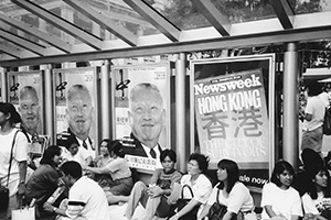 Filipino domestic helpers on a day off work, gathering under a bus shelter with adverts showing Tung Chee-hwa, Chater Road, Central, 29 June 1997