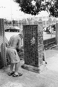 Tsang Tsou Choi, the 'King of Kowloon', writing calligraphic graffiti on street furniture near Victoria Park, towards Tai Hang, 27 September 1996