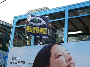 Man on tram with poster, showing solidarity with participants in a pro-democracy demonstration, Causeway Bay, 4 December 2005