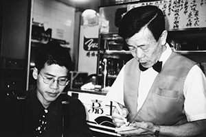 Artist Kacey Wong, with waiter taking the order in a Wanchai restaurant, 3 December 1996