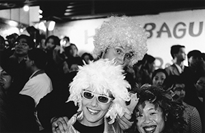 New Year's eve revellers in Lan Kwai Fong wearing chicken feather wigs and carrying a rubber chicken in reference to the then-current 'bird-flu' epidemic, 31 December 1997