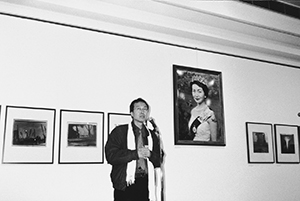 Benny Chia giving an opening speech at a Fringe Festival photography exhibition in the City Hall, with Holly Lee's digital image The Great Pageant Show, Central, 21 January 1998