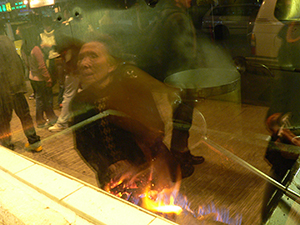 Roasting a pig, with reflections of a street scene, Kowloon City, 5 February 2005