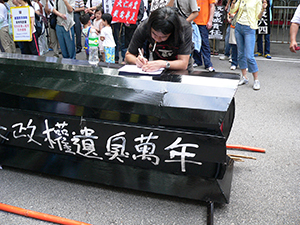 Leung Kwok-hung using a coffin as a writing desk, at the end of the June Fourth march from Victoria Park to Central, 29 May 2005