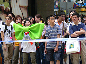 Participant in the democracy rally and march, with giant bowtie in comic reference to Donald Tsang, Hong Kong's then Chief Executive, who habitually sports one (albeit of more modest proportions), near Sogo department store, Causeway Bay, 1 July 2005