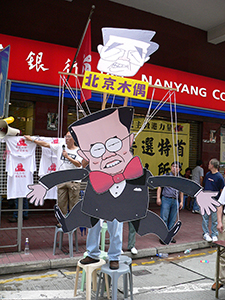 Donald Tsang being portrayed as a puppet of Beijing (in form of Chinese leader Hu Jintao), alongside the democracy march between Causeway Bay and Wanchai, 1 July 2005