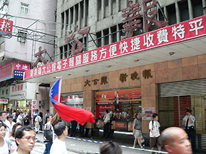 Participants waving a Taiwanese flag outside Ta Kung Pao building during the annual pro-democracy march, 1 July 2007