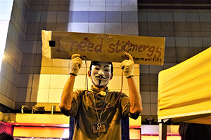 Man holding a sign promoting stigmergy at the Admiralty Umbrella Movement occupation site, Harcourt Road, 10 December 2014