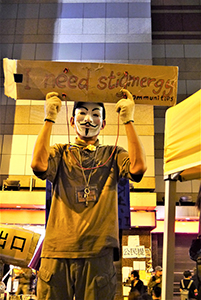 Man holding a sign promoting stigmergy at the Admiralty Umbrella Movement occupation site, Harcourt Road, 10 December 2014