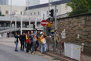 Removing a sticker from a traffic light, on the final day of the Admiralty Umbrella Movement occupation site, Harcourt Road, 11 December 2014