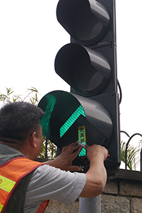 Removing a sticker from a traffic light, on the final day of the Admiralty Umbrella Movement occupation site, Harcourt Road, 11 December 2014