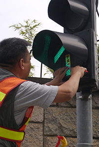 Workman removing a sticker from a traffic light, on the final day of the Admiralty Umbrella Movement occupation site, Connaught Road Central, 11 December 2014