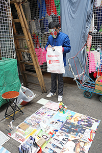A person in a mask running a street market stall, Sham Shui Po, 21 February 2015