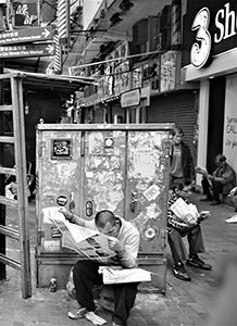 Man reading a newspaper on the street, Fuk Wa Street, Sham Shui Po, 21 February 2015