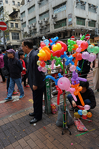 A person twisting balloons at the junction of Fuk Wing Street and Pei Ho Street, Sham Shui Po, 21 February 2015