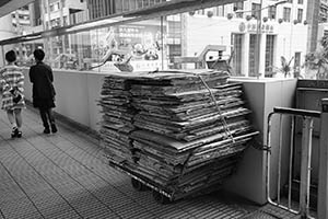 A stack of flattened cardboard boxes on a trolley on an overhead walkway, Central, 29 March 2015