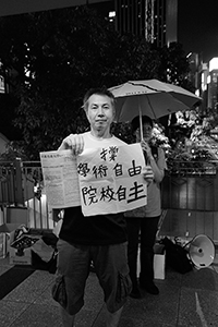 A man holding a banner supporting academic freedom on an overhead walkway, Wanchai, 1 September 2015