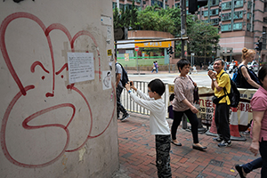 Boy taking a photo of a political sticker on the wall of a building, Fat Hing Street, Sheung Wan, 4 April 2016