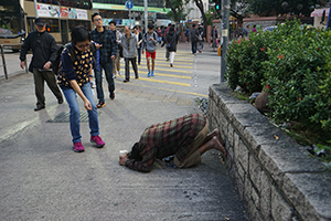 A lady giving money to a beggar on the street, Kowloon, 31 December 2016