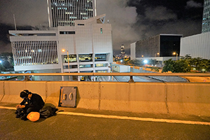 Protester on the Harcourt Road flyover, with the PLA Barracks behind, 21 June 2019