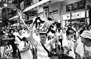 Man holding a sign on the  pro-democracy march from Victoria Park to Central, 1 July 2004