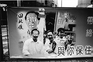 Defaced roadside banner of Liberal Party politician James Tien photographed during a pro-democracy march from Victoria Park to Central, 1 July 2004