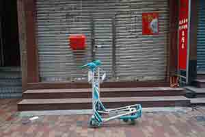 Airport trolley marooned outside a shop closed for the Lunar New Year holiday, Sheung Wan, 15 February 2018