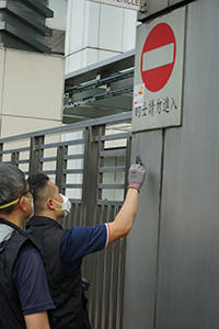 Police dusting for fingerprints at the entrance of the Liaison Office of the Central People's Government, after vandalism in a protest on the previous day, Sai Ying Pun, 22 July 2019