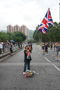 'Grandma Wong' waving a British flag near the Che Kung Temple, prior to an anti-extradition bill march to Sha Tin, 14 July 2019