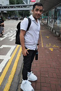 Visitor from the Philippines hoping to protect his new trainers in wet weather, Queensway, Admiralty, 6 October 2019