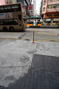 Yellow chains replacing railings, and graffiti written in wet concete that replaces pried-up paving stones, Nathan Road, Jordan, 22 December 2019