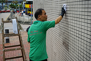 Worker cleaning graffiti from the wall of the Central Police Station, Chung Kong Road, Sheung Wan, 22 July 2019