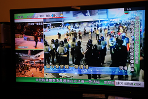 Live news on the television in a restaurant in Wanchai showing the police clearance operation at the Legislative Council, 2 July 2019