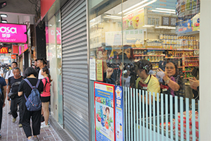 Staff in a shuttered Wellcome supermarket observe the protest activity outside, 'Reclaim Sheung Shui' protest against parallel traders from China, San Fung Avenue, 13 July 2019