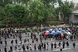 Protesters transferring supplies in a line, while others are holding up umbrellas to hide the removal of roadside railings, Sha Tin, 14 July 2019