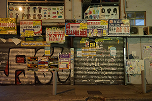 Graffiti, posters and advertisements on a closed shop, Wanchai, 26 September 2019