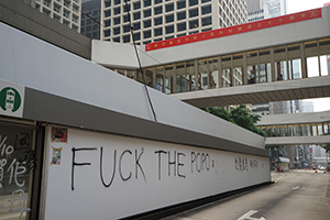 Graffiti on a tram stop hoarding and a banner on a footbridge, Des Voeux Road Central, 29 September 2019