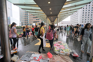 Foreign domestic helpers hold an informal market on a footbridge in Central, while protest activity and other foot traffic goes on around them, 6 October 2019