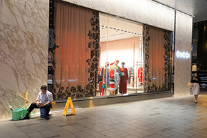 Cleaning worker outside a Christmas-themed shop window display at Gucci, Queen's Road Central, Central, 20 December 2019