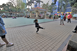 Small girl with a powerful kick, in a playground in Yau Ma Tei, Kowloon, 26 December 2019